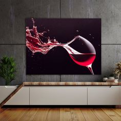 a wine glass with red liquid splashing out of it in front of a grey wall