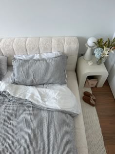 a bed that has some pillows on top of it and a pair of shoes next to it