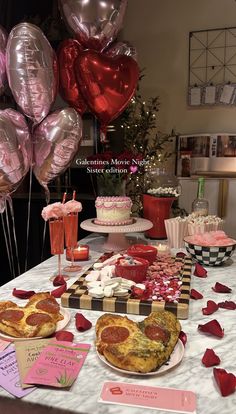 a table topped with lots of different types of food and balloons in the shape of heart shapes