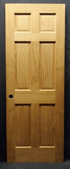 a wooden door is shown against a black wall with a hole in the bottom half