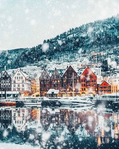 a snowy scene with boats and houses in the water