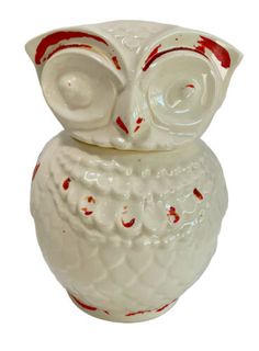 a white ceramic owl with red accents on its body