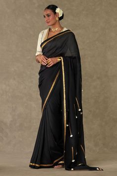 Black organza saree with contrast metallic gota and ivory fringe tassel embroidered pallu. Paired with cotton linen unstitched blouse piece.
Components: 2
Pattern: Embroidered
Type Of Work: Gota and Tassel Work
Fabric: Saree: Organza, Blouse: Cotton Linen
Color: Black
Other Details: 
Contrast kiran lace border
Note: The stitched blouse worn by the model is not for sale
Disclaimer: The actual print-placement and colour of the product may slightly vary slightly from the image shown.
Occasion: Sang Festive Chanderi Traditional Wear With Tassels, Festive Traditional Chanderi Wear With Tassels, Festive Silk Dupatta With Tassels, Bollywood Saree With Tassels For Wedding, Silk Dupatta With Tassels In Traditional Style, Traditional Silk Dupatta With Tassels, Navratri Chanderi Dupatta With Tassels, Festive Wedding Saree With Tassels, Traditional Blouse Piece With Latkans For Eid