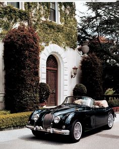 an old black car parked in front of a house