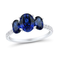 three stone ring with blue sapphires and diamonds on the sides, set in white gold