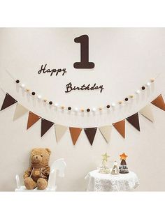 a teddy bear sitting in front of a birthday banner with the number one on it