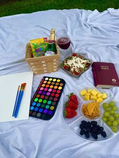 the picnic is ready to be eaten on the blanket with wine, fruit, and books