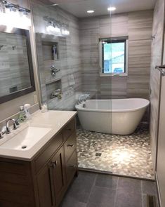 a bathroom with a bathtub, sink and large mirror on the wall next to it