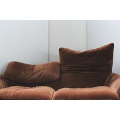 a brown couch sitting in front of a wall with two pillows on top of it