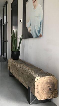 a wooden bench sitting in front of a painting on the wall next to a potted plant