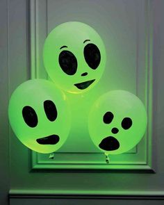 three glow green balloons with faces on them