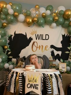 a baby in a high chair eating cake at a wild one birthday party