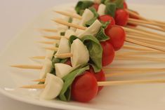 toothpicks with tomatoes, cheese and lettuce are arranged on a white plate