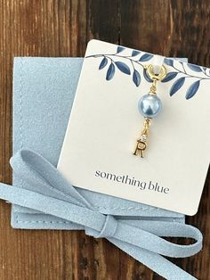 a card with a blue ribbon tied around it and a gold charm attached to it