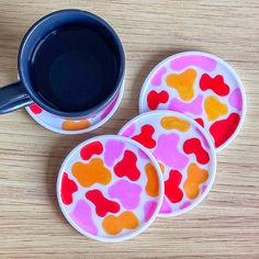 three coasters with hearts painted on them next to a coffee cup and saucer