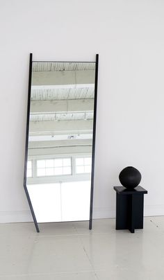 a large mirror sitting on top of a white floor next to a black table and chair