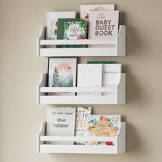 three white shelves with books on them against a wall in a nursery or kids's room