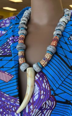 This Tribal necklace makes with indigo imported beads from Gambia. A true stand out and amazing. Piece . This precious necklace is s4 inches in length.  long. This necklace would look great on solid color garments.The color of the handmade jewelry make you calm and reminds of the calm sounds of the ocean. The horn pendant is a replica horn. Don't delay order yours today, Traditional Wooden Beaded Necklaces For Festivals, Unique Wooden Beads Necklace For Festivals, Unique Wooden Beaded Necklaces For Festivals, Unique Beaded Necklaces With Wooden Beads For Festivals, Artisan Large Beads For Festival, Artisan Large Beads For Festivals, Artisan Fair Trade Beaded Necklace For Festivals, Traditional Blue Wooden Beads, Traditional Wooden Beaded Necklaces With Round Beads