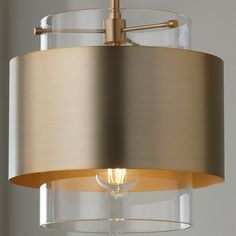 a light that is hanging from the ceiling with a glass shade over it and a metal rod