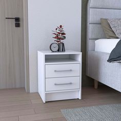 a white nightstand with a clock on it next to a bed