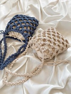 two crocheted bags sitting on top of a white sheet