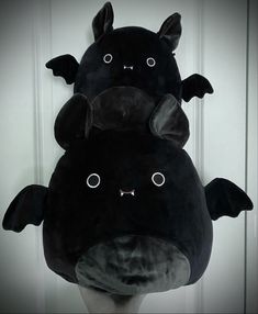 two black stuffed animals sitting on top of each other in front of a white door