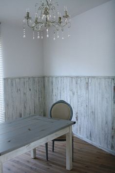 an empty room with a table, chair and chandelier