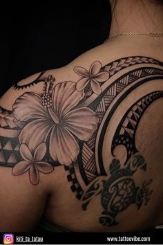 the back of a woman's shoulder with a flower and turtle tattoo on it