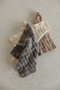 four knitted dishcloths sitting on top of a counter