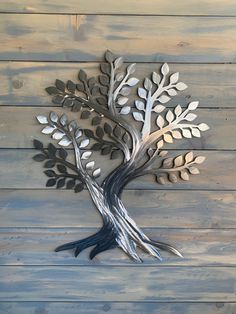 a metal tree sculpture sitting on top of a wooden wall