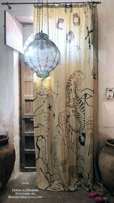 a bathroom with a shower curtain that has drawings on it and lights hanging from the ceiling