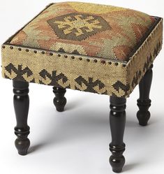 a foot stool with wooden legs and a colorful pattern on the backrest, sitting in front of a white background