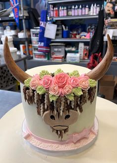 a cake decorated with flowers and an animal's head on top of a table