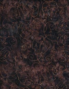 a brown and black area rug with swirly designs on the top, in front of a dark background