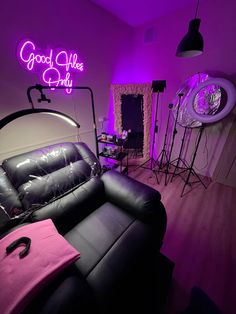 a living room with black leather furniture and purple lighting on the walls, along with neon signs