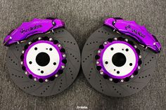 two purple brake discs on top of each other in front of a carpeted floor