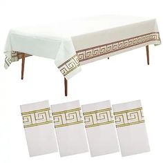 a white table cloth with gold greek border on it and four placemats in front