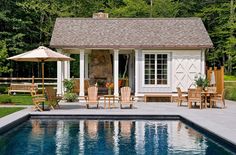 a pool with chairs and an umbrella next to the swimming pool in front of a house