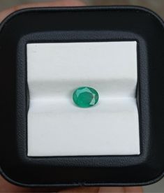 a ring with a green stone in it sitting on top of a white and black box