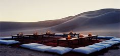 the desert is covered in sand and lit candles are set up on top of pillows