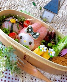 a wooden boat filled with sushi and vegetables on top of a white tablecloth