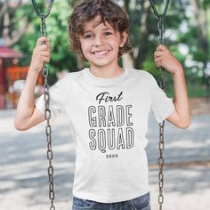 a young boy is smiling while holding onto a swing with the words coolest cat in school on it