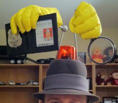 a man wearing a gray hat and holding up two bananas on top of his head