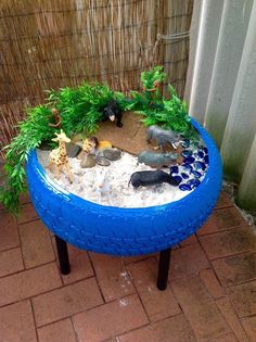 a blue table with plants and rocks in it on a brick floor next to a bamboo fence