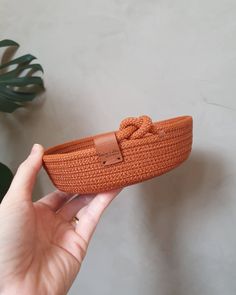 a hand holding an orange shoe with a knot on it