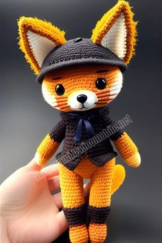 a small stuffed animal is wearing a hat and scarf on it's head, while being held by a hand