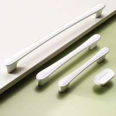 three white kitchen utensils sitting on top of a green counter next to a knife