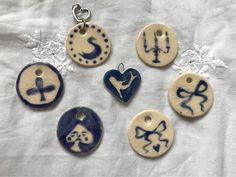 six ceramic buttons with designs on them sitting on a white cloth covered tablecloth in various shapes and sizes