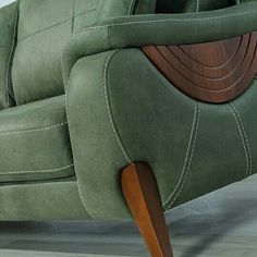 a green couch with wooden legs and arm rest