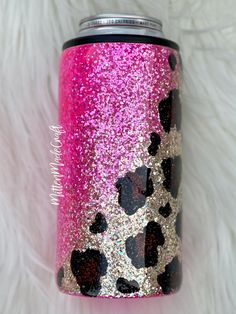 a pink and black leopard print can cooler with glitter hearts on the side, sitting on a white fur background